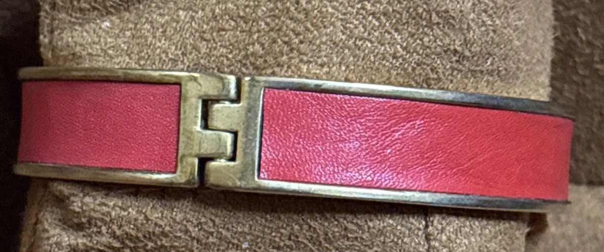 Henri Bendel red leather bangle features a gold-tone metal bar set rhinestones.