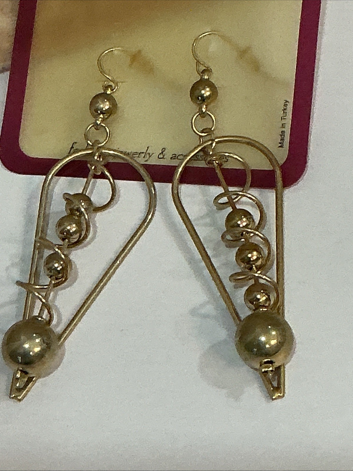 Esmer brand gold-tone dangle earrings feature a distinctive geometric triangle