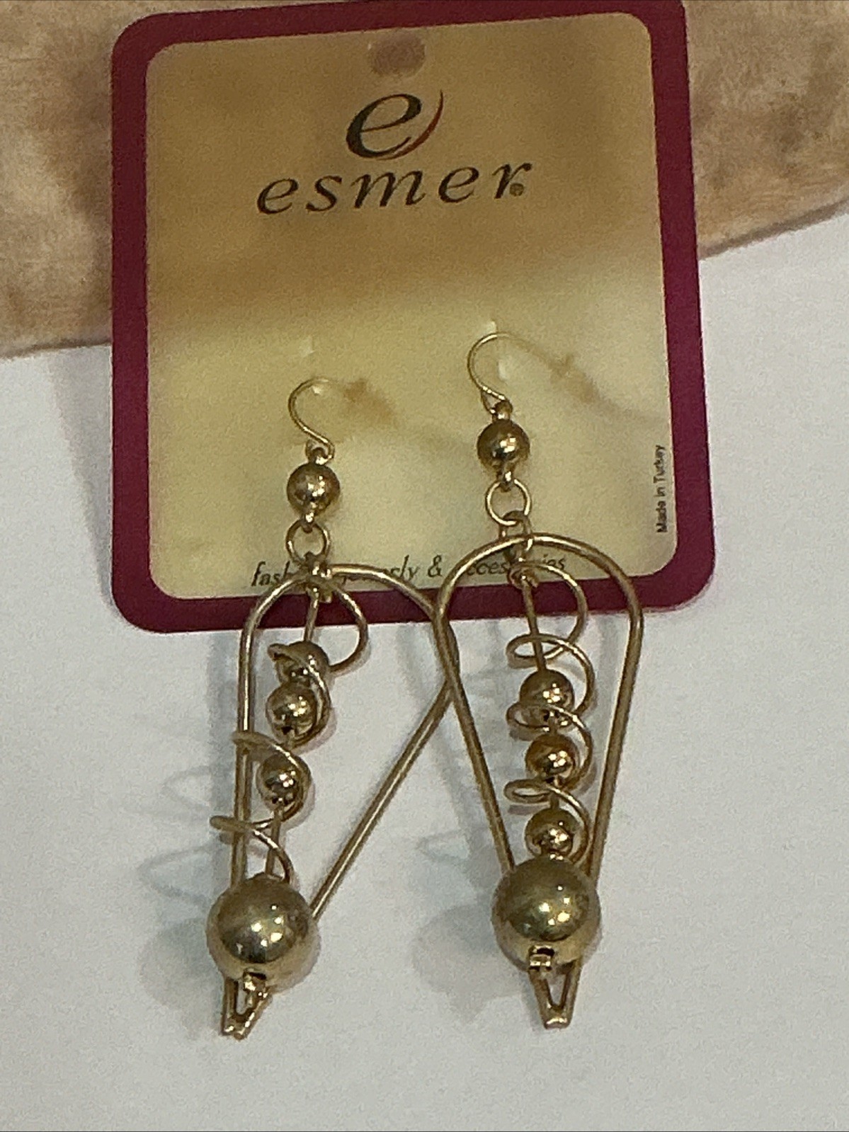 Esmer brand gold-tone dangle earrings feature a distinctive geometric triangle