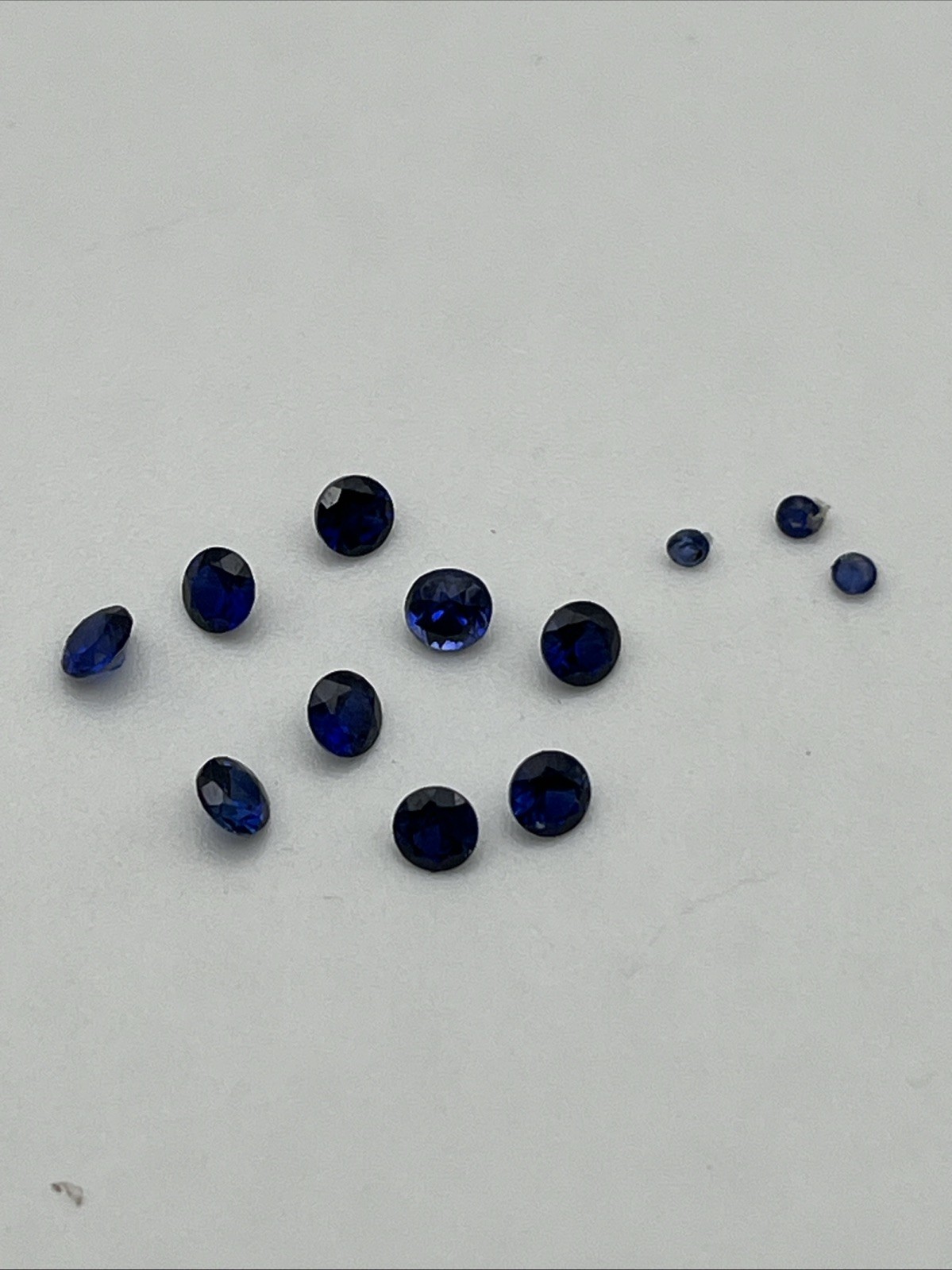 Nine 3 Mm And Three 1.5 Mm Round Faceted Synthetic Blue Sapphires